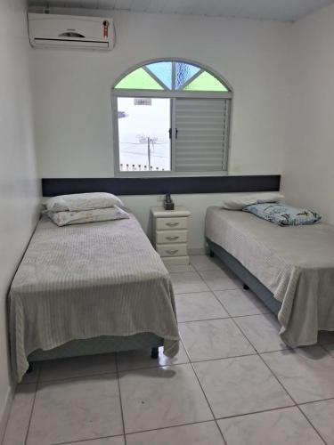 a bedroom with two beds and a window at Apartamento no Costão do Pântano do Sul in Florianópolis