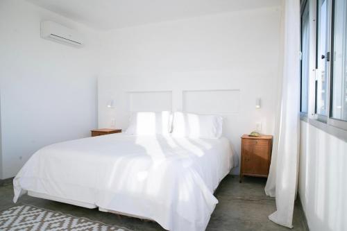 a white bedroom with a white bed and a window at La Posta Beach Hotel in Punta del Este