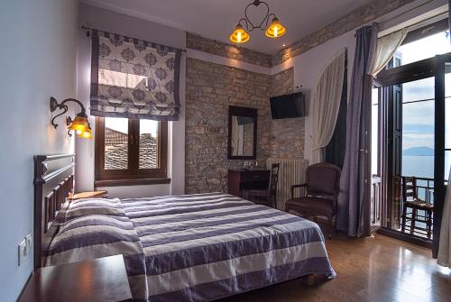 a bedroom with a bed in a room with windows at Guesthouse Aktaion in Afissos
