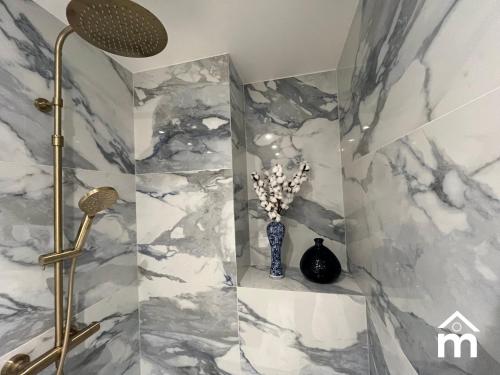 La salle de bains est pourvue d'une douche et d'un mur en marbre. dans l'établissement Paris Marais Saint Paul by Melvane, à Paris