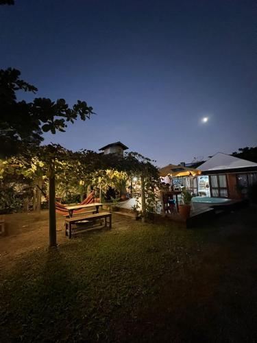 a park with a bench and a house at night at Hostel Bombinhas in Bombinhas