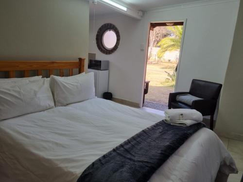 a bedroom with a bed and a chair and a window at Emerald Guesthouse in Kempton Park