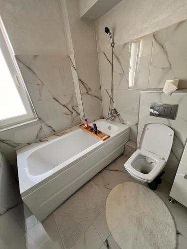 a white bathroom with a tub and a toilet at Lake View Apartment Iasi in Valea Lupului