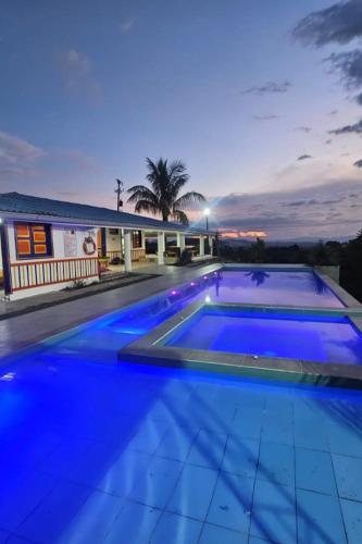 a large swimming pool with blue lighting in front of a house at Finca Nuevo Monarca in Pereira