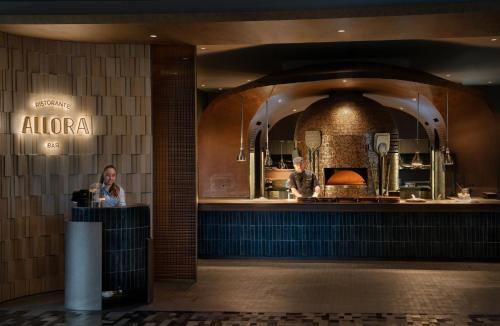 a woman standing at a counter in front of a restaurant at Crowne Plaza Changi Airport by IHG in Singapore