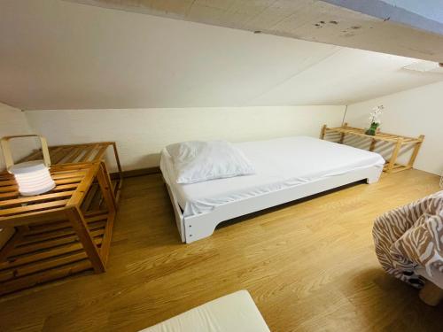 une chambre avec un lit blanc et un parquet dans l'établissement Le 7ème Ciel - 3 étoiles, à Thonon-les-Bains