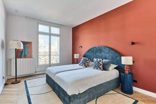 une chambre avec un grand lit avec un mur orange dans l'établissement Luxueux Appartement familial 5 BD, Parc Monceau, à Paris