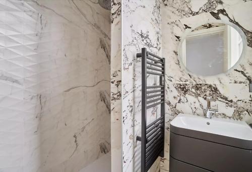 une salle de bain avec un lavabo et un miroir dans l'établissement Luxueux Appartement familial 5 BD, Parc Monceau, à Paris
