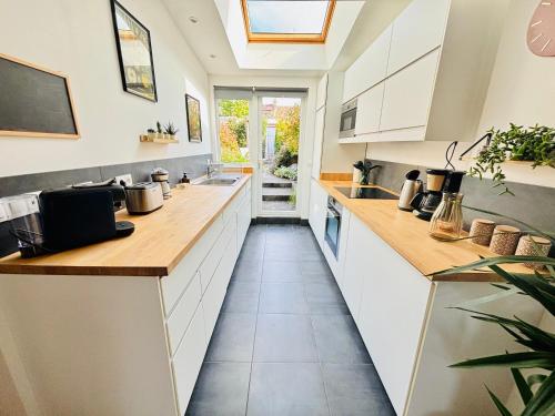 une cuisine avec des armoires blanches et des comptoirs en bois dans l'établissement Maison au calme quartier Lancrel, à Aleçon