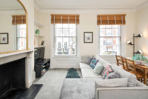 a living room with a couch and a fireplace at High-ceiling Gorgerous Victorian flat with private garden - 3 mins to Hyde Park, Kensington Palace, 8 mins NottingHill, High Street Kensington station in London