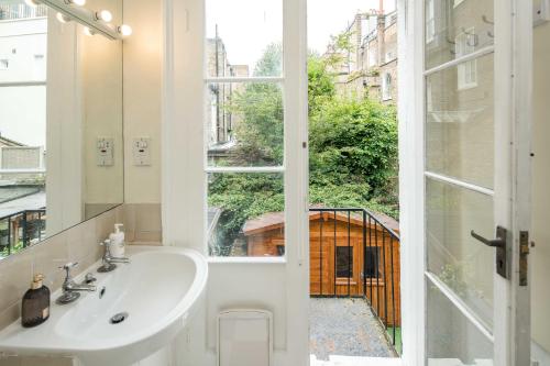 a bathroom with a sink and a window at High-ceiling Gorgerous Victorian flat with private garden - 3 mins to Hyde Park, Kensington Palace, 8 mins NottingHill, High Street Kensington station in London