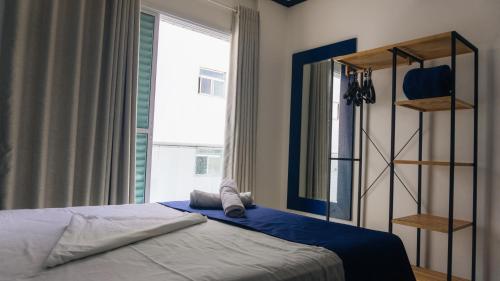 a bedroom with a bed and a large window at Apartamentos Primavera Guarujá in Guarujá