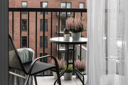 a table and a chair on a balcony with a building at NEW #Madalińskiego57 - city center, new bulding, 2 bedrooms, 2x double beds and a fold-out sofa, separate kitchen, air conditioning, balcony, underground parking, self check in 24h, internet, Netflix, coffee machine, washing machine,1 km to the railway in Wrocław