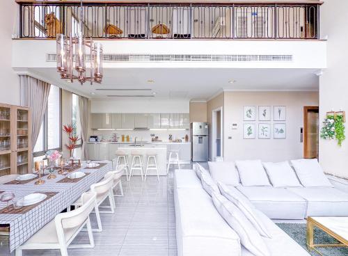a living room with white furniture and a kitchen at Sukhumvit-Thonglor Luxury Pool Club Villa 5 Mins to BTS 素坤逸-通羅 豪華會所泳池別墅 5分鐘到達地鐵 in Bangkok