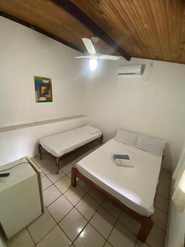 a room with a white bed and a bench at Doce Lar Hospedaria in Lençóis