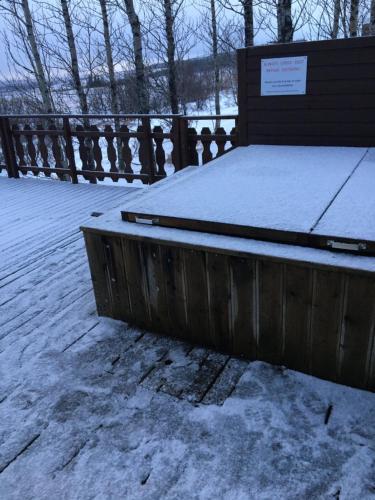 a bench covered in snow next to a fence at Úthlíd Cottages in Úthlid