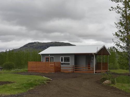 a small cabin with a fence and a house at Úthlíd Cottages in Úthlid