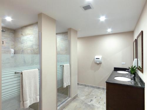 a bathroom with two sinks and a shower at Coconut Court Beach Hotel in Bridgetown
