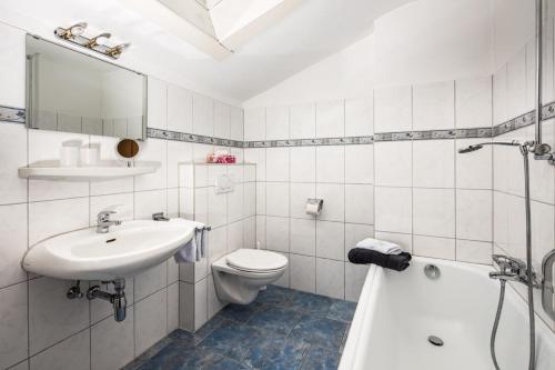 a bathroom with a sink and a toilet and a tub at Sportpension Färbinger in Berchtesgaden
