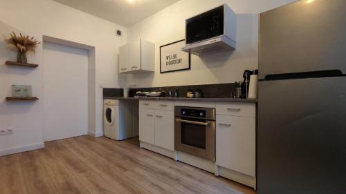  La cuisine est équipée de placards blancs et d'un réfrigérateur. dans l'établissement T2 Cosy - Proche place Verdun, à Castelnaudary