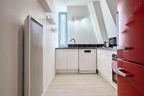 La cuisine est équipée de placards blancs et d'un réfrigérateur rouge. dans l'établissement Duplex cosy et lumineux au pied du tram, à Mouvaux