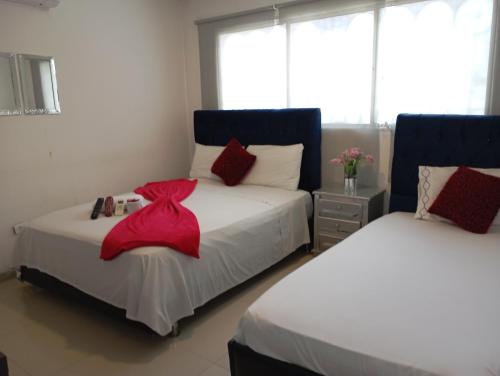 - une chambre avec 2 lits et des draps rouges dans l'établissement Hostal altos de riomar Barranquilla inn, à Ciudad Jardín