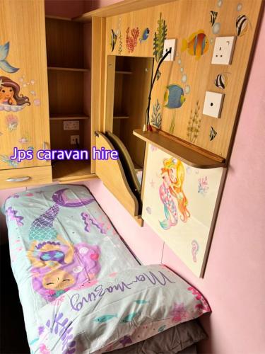 a room with a bed and a cabinet with mermaid stickers at Jps caravans in Kinmel Bay