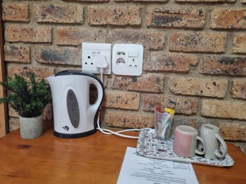 a table with a coffee maker and cups on it at Emerald Guesthouse in Kempton Park