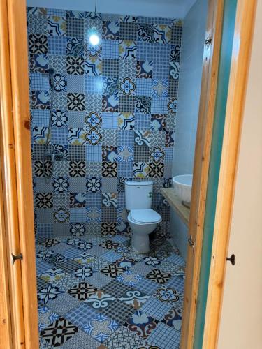a bathroom with a toilet and a tiled wall at Al Kasbah Resort in El Jadida
