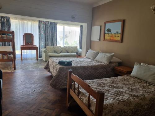 a hotel room with two beds and a couch at Emerald Guesthouse in Kempton Park