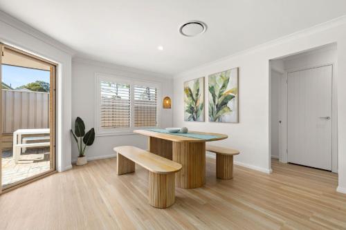 a living room with a table and two benches at Pipis Huskisson by Experience Jervis Bay in Huskisson