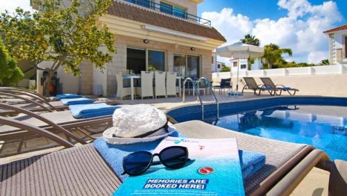 a table with a hat and sunglasses next to a swimming pool at Sonja in Paralimni