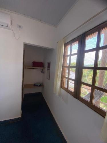 an empty room with two windows and a shelf at Doce Lar Hospedaria in Lençóis