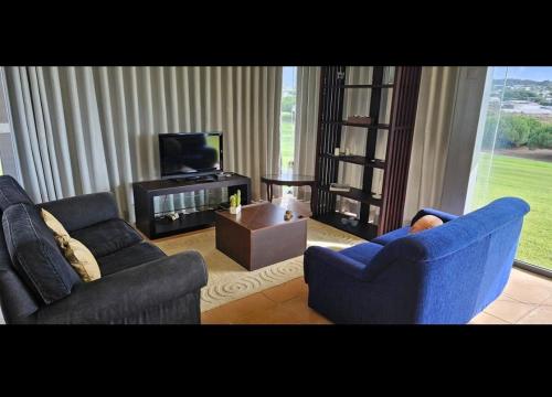 a living room with two blue chairs and a television at Casa Oliveira in Casa da Ferraria