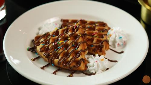 a plate of food with waffles and whipped cream at InterContinental Marine Drive Mumbai by IHG in Mumbai