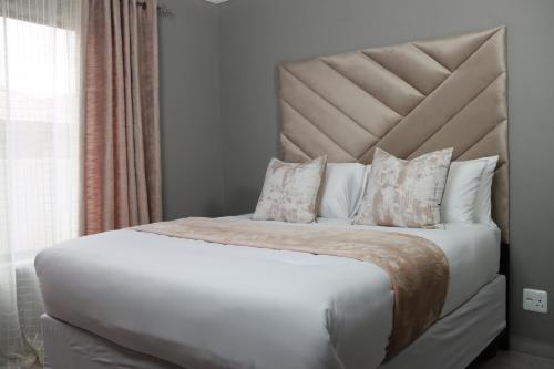 a bedroom with a large bed with white sheets and pillows at Luxuryo in Zeerust