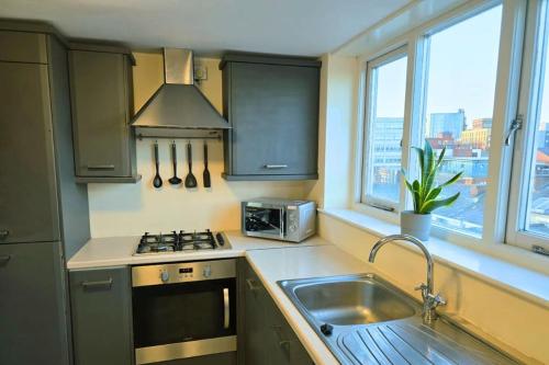cocina con fregadero, fogones y ventanas en Stylish City Centre Apartment with Parking, en Preston