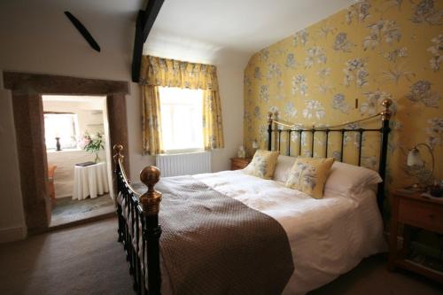 um quarto com uma cama grande e papel de parede amarelo em Reddivallen Farmhouse em Boscastle