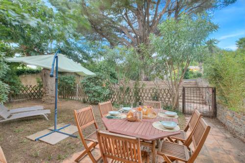 une table en bois avec des chaises et un parasol dans l'établissement Villa Azzurra Front Beach - Happy Rentals, à Saint-Tropez