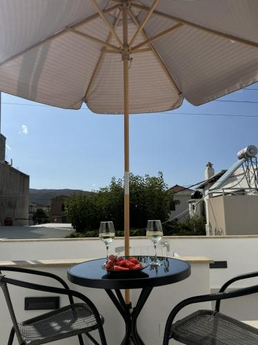 a table with an umbrella and two glasses of wine at Kasteli loft apartment in Kissamos