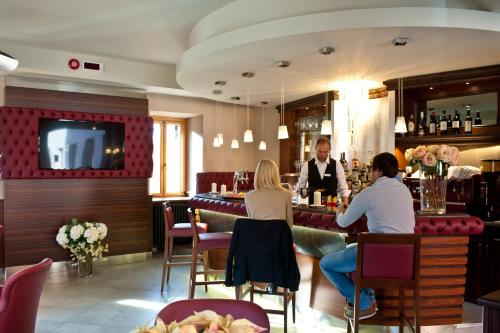 a group of people sitting at a bar in a restaurant at Hotel Garnì Cristallo in Ponte di Legno