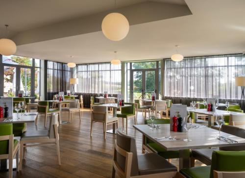 a restaurant with tables and chairs and windows at Holiday Inn Huntingdon Racecourse by IHG in Huntingdon