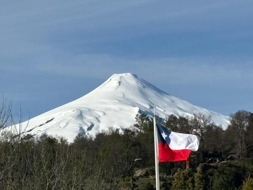 a flag in front of a snow covered mountain at Departamento en condominio in Pucón