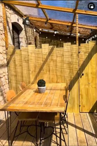 a wooden table with a potted plant on a patio at Gîte La Grange de La Trigalle avec spa professionnel privatif in Valognes