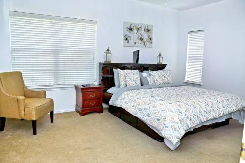 a bedroom with a bed and a chair and windows at Spacious 4-bedroom house with AC, Wi-Fi superb in the Heart of Arlington, TX! in Johnsons Station