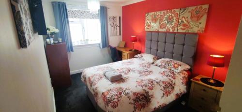 a bedroom with a bed with a red wall at Double room in riverside apartment in Glasgow