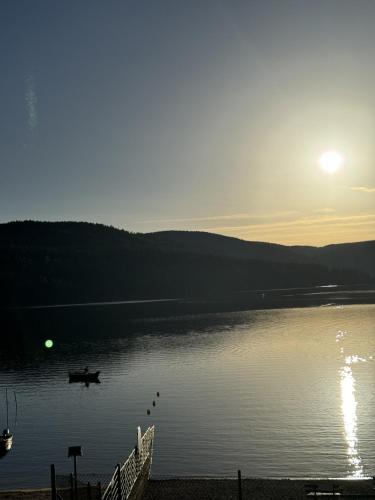 a boat on a lake with the sun setting at Chalet Schluchsee Ferienwohnung in Schluchsee