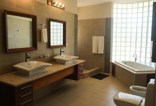 a bathroom with two sinks and a tub and a mirror at Luxury oceanfront condo, enjoy it ! in Cabarete