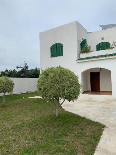 a white building with a tree in front of it at Villa Soukra Avenue Fattouma Bourguiba in La Soukra