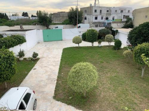 a car parked in a yard with trees and bushes at Villa Soukra Avenue Fattouma Bourguiba in La Soukra